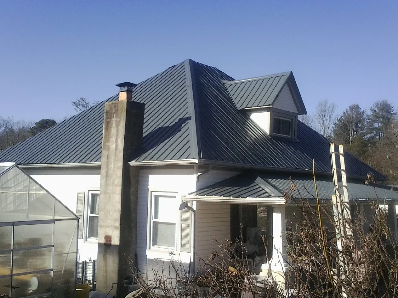 Dark blue standing seam metal roof on a white farmhouse with dormer — Slate & Tile Roof Repair by Roofing Brothers in Camak