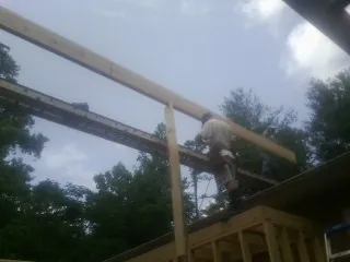 Carpenter setting a ridge beam over a new addition frame — Ice Dam Removal by Roofing Brothers in Camak