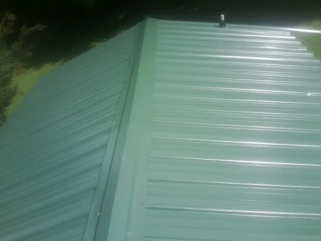 New green metal panels meeting at the ridge of a roof — Flat Roof Repair work by our crew in Camak