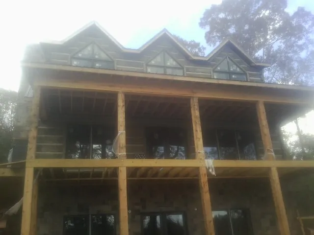 Dormers and porch framing on a large log home under construction — Roof Coating work by our crew in Camak