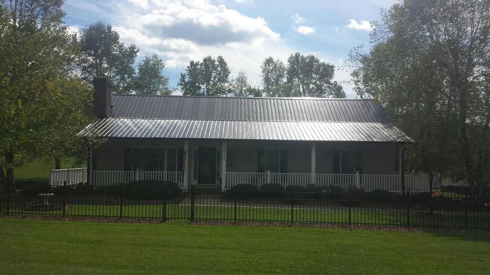 Gray metal roof on a brick ranch with a full width front porch — Gutter Guard Installation work by our crew in Camak