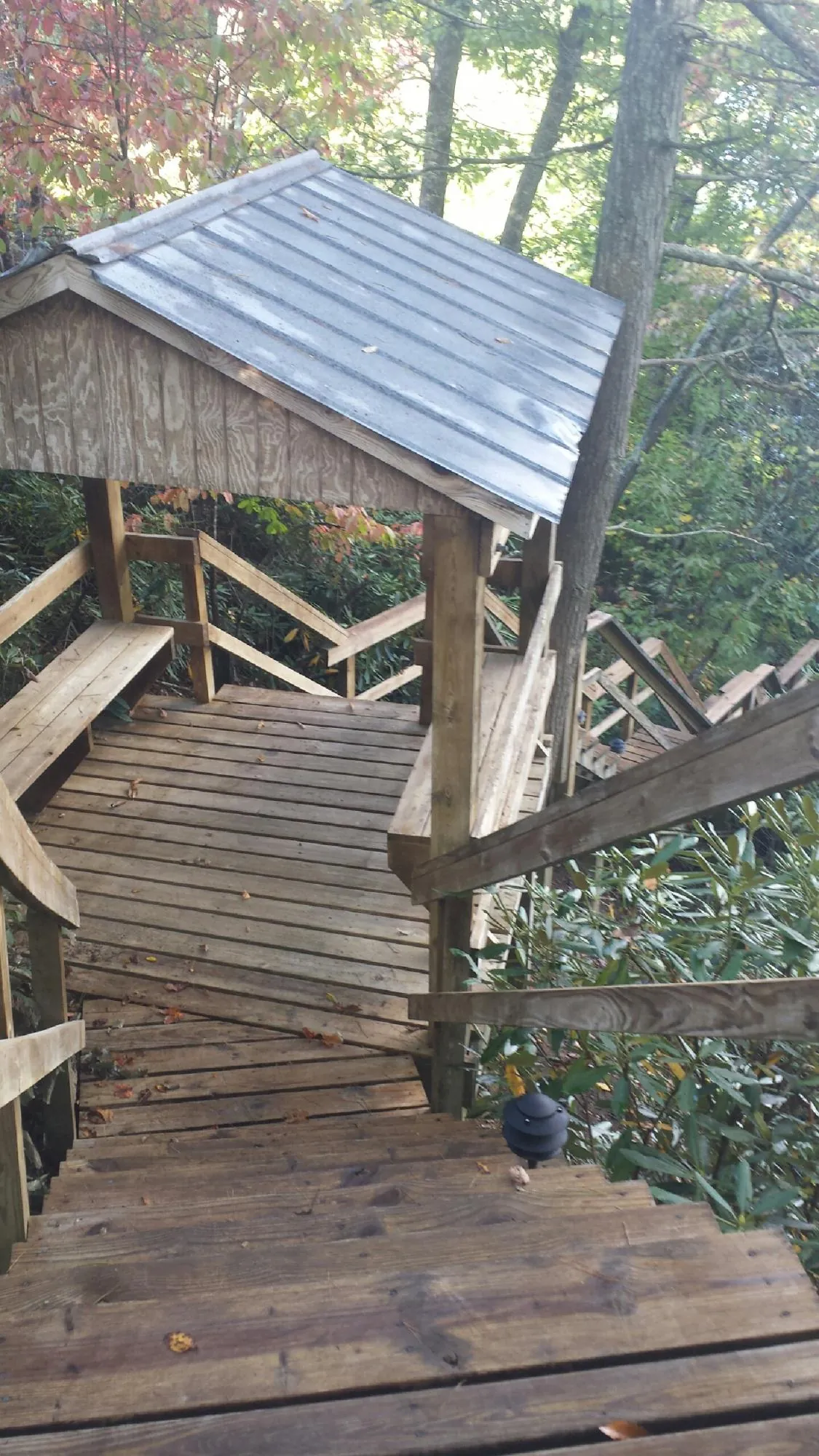 Metal roofed shelter over wooden steps on a wooded walkway — Skylight Repair & Installation work by our crew in Camak
