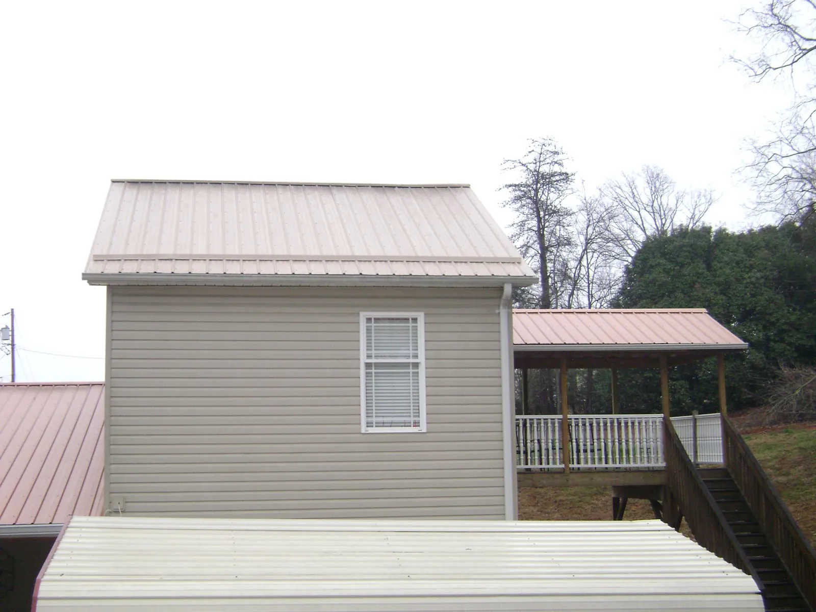 Tan metal roofs on a two story addition and attached porch, from a Roof Replacement job in Camak