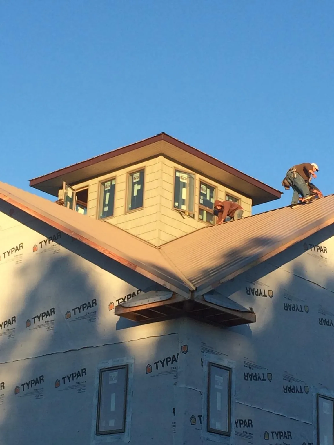 Roofers working around a rooftop cupola on a new metal roof at sunset — Roof Waterproofing in Camak by Roofing Brothers